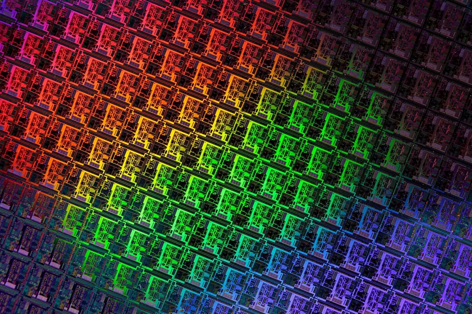 Ausschnitt eines prozessierten Siliciumwafers mit regelmäßig angeordneten Chips, die in Regenbogenfarben schimmern
